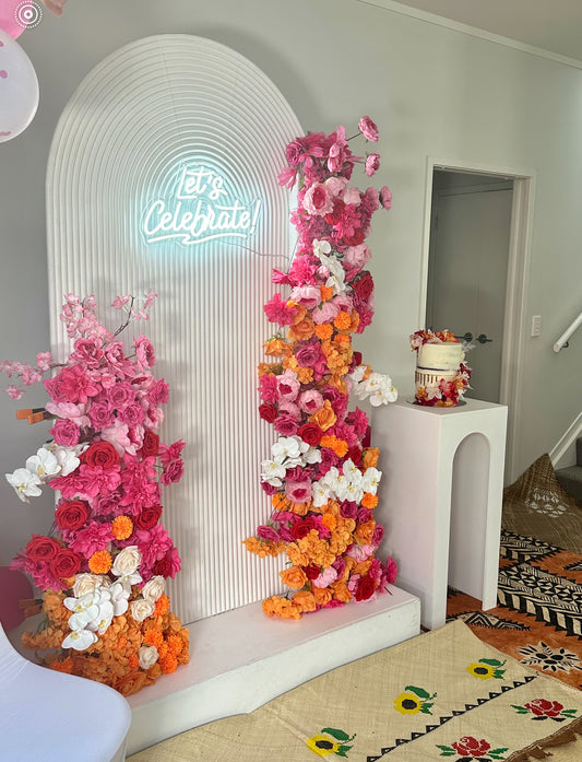 Ripple and floral backdrop arrangment with neon Let's Celebrate